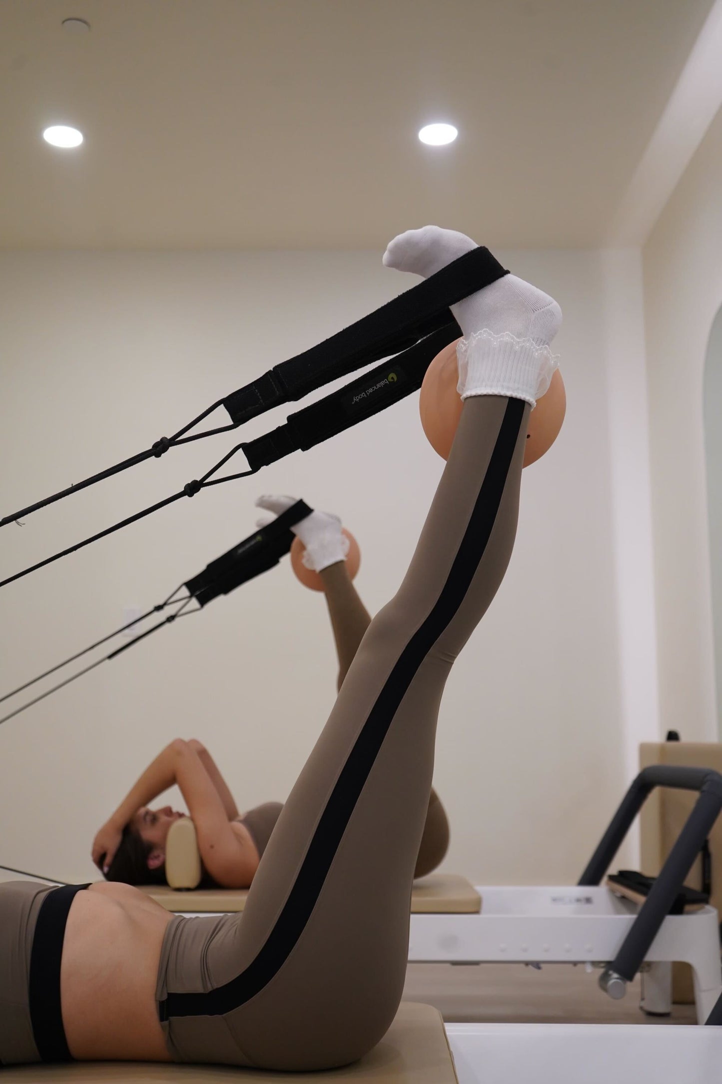 woman in feet in pilates straps on reformer wearing lace ruffle grip socks